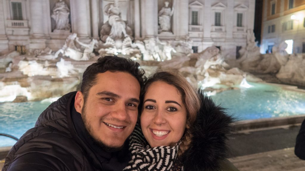 Casal viajando o mundo em frente a Fontana di Trevi em Roma.